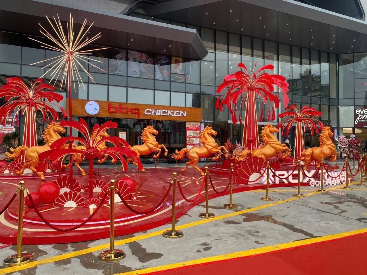 Booth trang trí sự kiện ngoài trời sau khi thi công, cụm cây đỏ, tuần lộc vàng và thảm đỏ trước sảnh tòa nhà