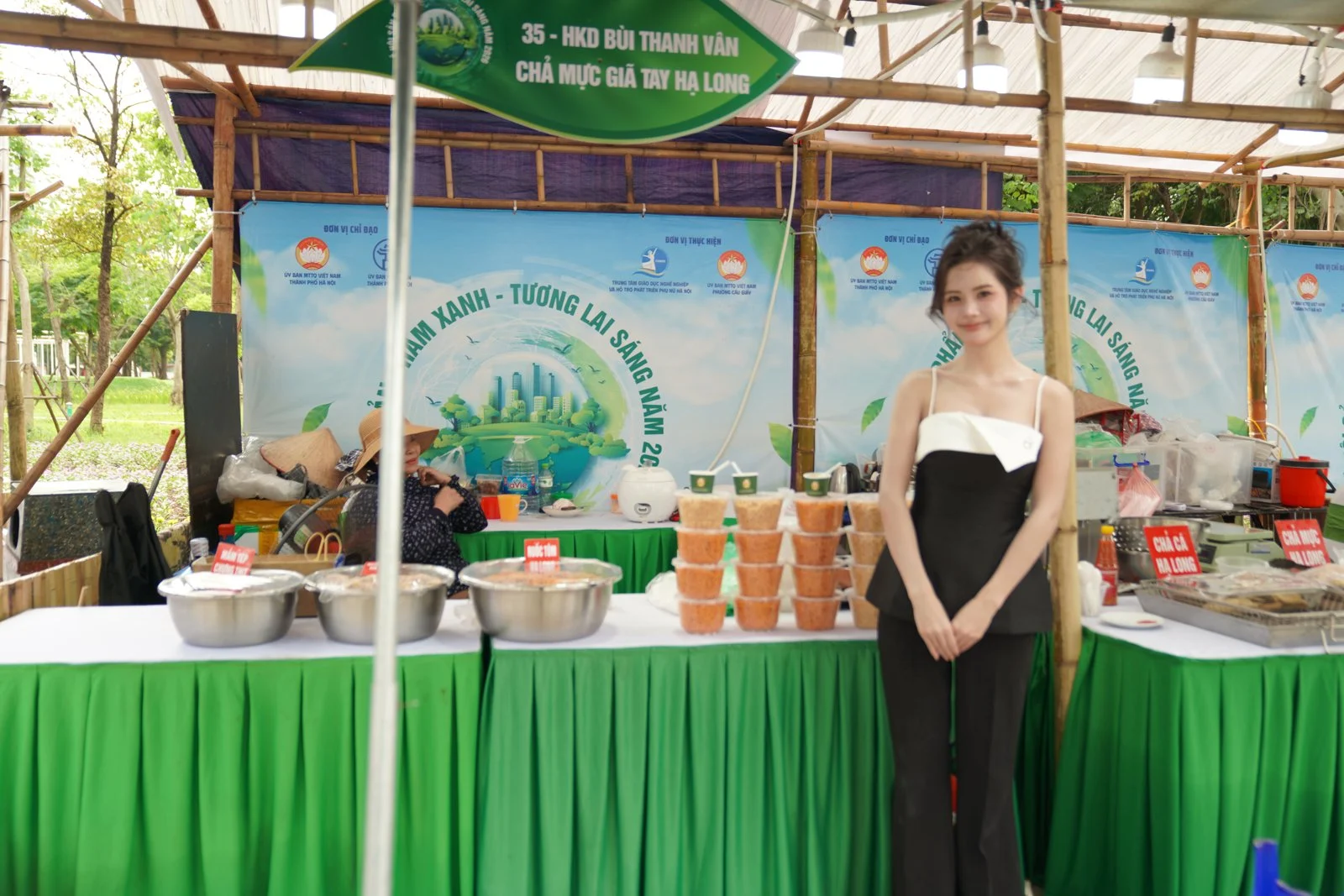 Quầy trưng bày và bán hàng tại một hội chợ ngoài trời, khăn bàn xanh và backdrop in bạt
